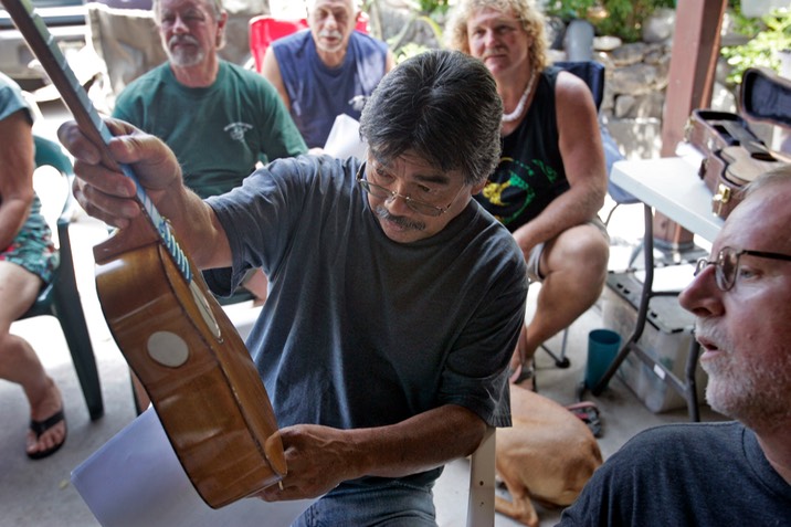 Rodney Cruzat examines an ukulele built of ‘ulu wood by Bob Gleason