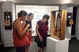 01 Exhibit visitors study an ukulele made by Bob Gleason