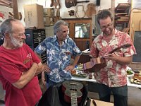 21 - Devon Rogers (R) examines the broken neck of Ernesto Bonilla's handmade instrument as Gary Casel (L) and Charles Newcomb look on