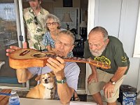 05 - Chuck Bennett holds Mike Perdue's uke as Mats Fogelvik (L-R), Pat and Gary Cassel take a look. Taco the dog is unimpressed